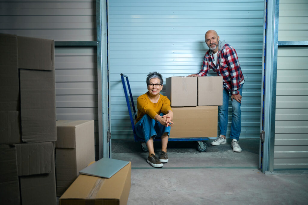 Smiling couple with a cartful of boxes in an Encore Deliveries storage unit.